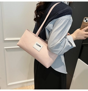 Detail of light pink glossy leather underarm bag with thin straps and white label patch