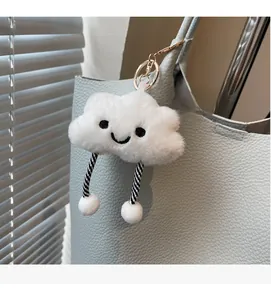 White plush cloud charm with embroidery and striped legs on a blue bucket bag