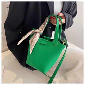 Close-up of green lychee leather bucket bag with printed scarf detail on handle