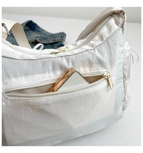 Détail du sac bandoulière en nylon blanc avec poches zippées et sangle ajustable