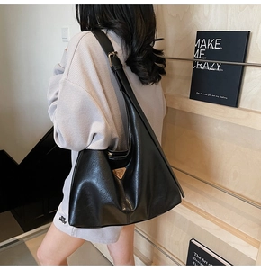 Detail of black glossy PU leather tote bag with golden triangle logo and wide shoulder strap