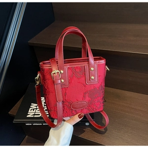 Detailed close-up of wine red bridal handbag with floral lace embroidery and strap