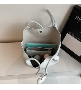Spacious interior of white lychee leather bucket bag holding a tablet and umbrella