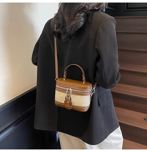 Port en bandoulière d'un sac boîte vintage avec bordure en cuir marron sur escalier