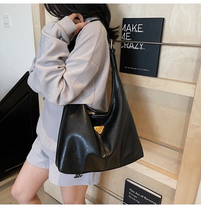 Close-up of black tote bag featuring golden triangle metal logo and premium leather texture