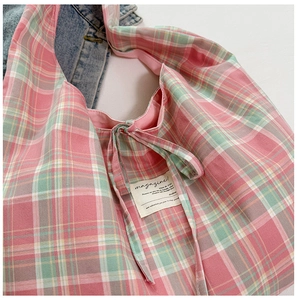 Gros plan d'un sac cabas à carreaux rose et vert avec détail étiquette magazine
