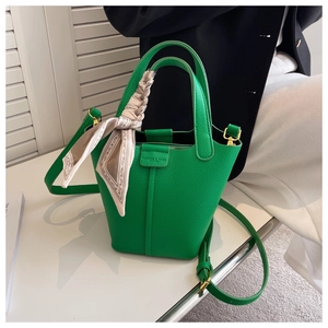 Detail of green pebble leather bucket bag with silk scarf and gold hardware accessories
