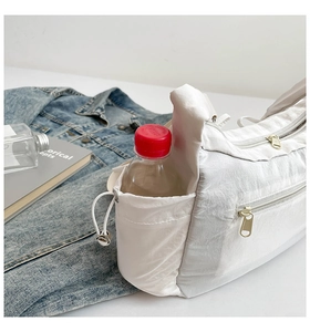Détail du sac bandoulière en nylon blanc avec poche latérale à cordon pour gourde ou bouteille