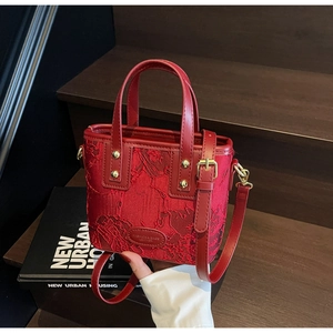 Detail of red bridal handbag with floral jacquard fabric and golden metal accents