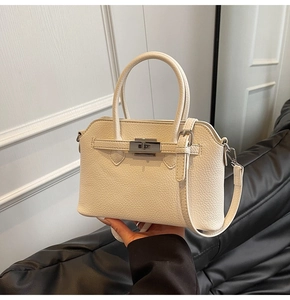 Detail van gebroken witte handtas met lychee-patroon, zilveren slot en metalen accenten
