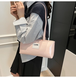 Pink patent leather shoulder bag with CLEAR heart logo shown on a model outfit