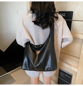 Lifestyle shot of large black tote bag with wide strap and triangle metal detail