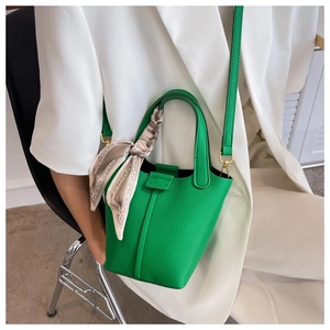 Close-up of bright green lychee grain bucket bag with floral scarf handle detail