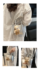Close-up of a silver metallic mini bag with H-stitch detail and a cute plush bear charm