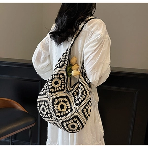 Detail of a handmade black and white granny square crochet hobo bag in retro folk style