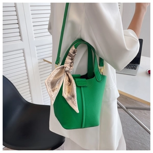Detail of bright green pebble leather bucket bag featuring a decorative floral silk scarf