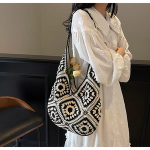 Close-up of hand-knitted floral tote bag featuring vintage black and white sun patterns
