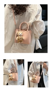 Detail of pink leather handbag with a cute plush bear pendant and adjustable shoulder strap