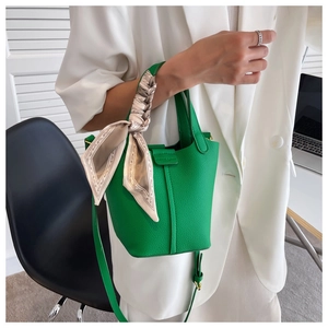 Close-up of green lychee leather bucket bag with printed silk scarf handle detail
