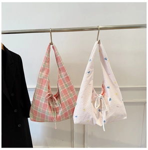 Détail de sacs hobo en toile à carreaux avec broderies et rubans de fermeture délicats