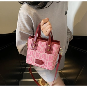 Detail of red wedding handbag featuring Xi character jacquard and leather trim