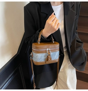 Detail of a brown and blue leather crossbody box bag with dual silver zippers and handle