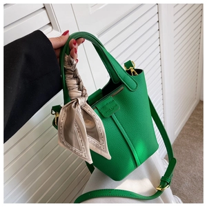 Detail of green bucket bag with lychee pattern leather and decorative silk scarf handle