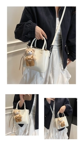 Detail view of a white leather bucket bag with a cute brown plush bear charm and strap