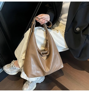 Detail shot of the large hobo bag in brown leather showing the metal triangle emblem