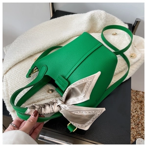 Detailed macro view of vibrant green lychee grain leather bucket bag with silk scarf