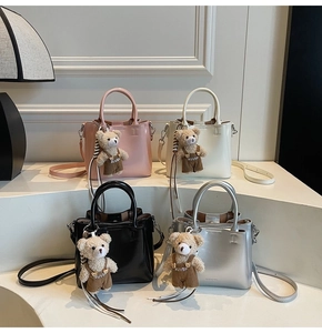 Four-color display of stylish tote bags with bear pendants on white display steps