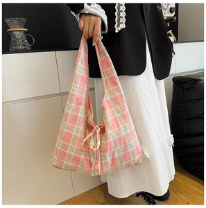 Détail d'un sac cabas à carreaux rose et vert orné d'un nœud et d'une texture douce