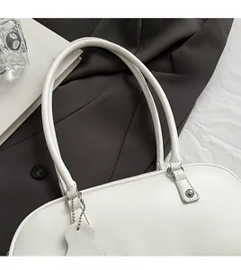 Close-up of white minimalist baguette bag featuring textured leather and dual handles