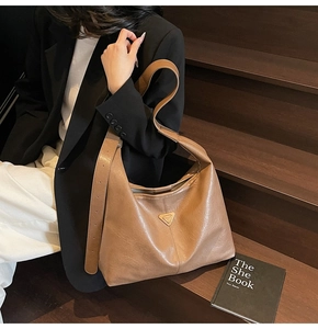 Detail of caramel faux leather tote bag showing glossy texture and triangle emblem