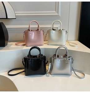 Four pastel PU leather crossbody bucket bags displayed on geometric steps in soft light