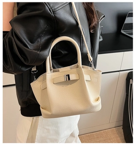 Close-up of cream leather bucket bag with silver buckle and lychee grain texture