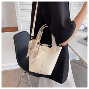 Close-up of white lychee pattern bucket bag with decorative silk scarf and thin strap