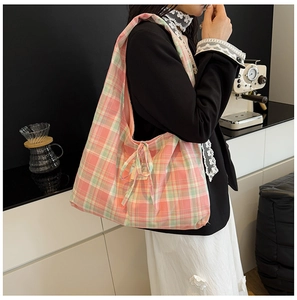 Détail du sac cabas à carreaux en toile avec nœud décoratif et bandoulière souple