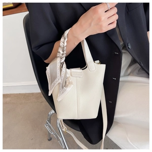 Detail of white lychee leather bucket bag with silk scarf handle and thin shoulder strap