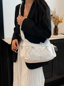 Sac bandoulière blanc en nylon avec nœud coulissant porté par un mannequin chic