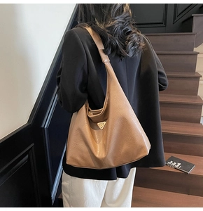 Close-up of a large caramel tote bag on a model standing on wooden stairs