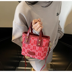 Detail of red wedding tote bag featuring woven double happiness motifs and gold rivets