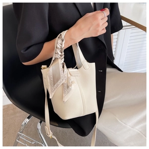 Detail of off-white lychee grain bucket bag with vintage pattern silk scarf on handle