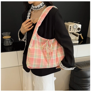 Détail du sac hobo en toile à carreaux rose et vert avec broderie sur bandoulière