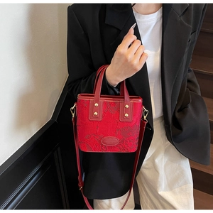Detailed shot of red jacquard wedding handbag with floral patterns and golden metal hardware