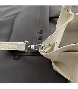 Detail of silver metal lobster clasp and D-ring on white litchi pattern leather bag