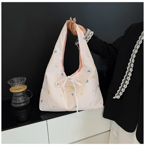 Détail du sac en toile à carreaux rose avec broderie colorée et ruban blanc