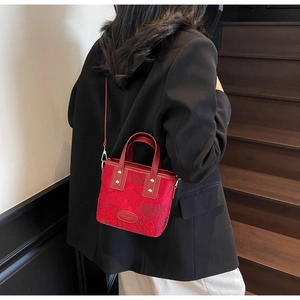 Detail of red embroidered bridal handbag with gold metal hardware and floral stitching