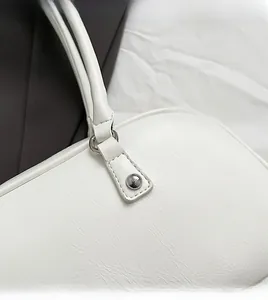 Detailed close-up of white leather bag with silver metallic studs and precise stitching