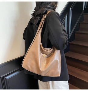 Brown leather hobo bag with glossy finish and metal buckle shown on a model